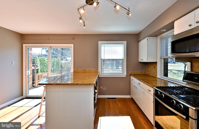 kitchen with white cabinetry, a peninsula, stainless steel appliances, and wood finished floors