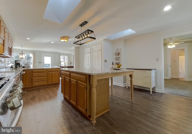 kitchen with hanging light fixtures, a skylight, dark wood-type flooring, and range