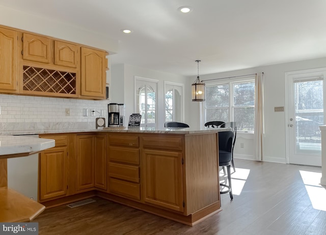 kitchen with light stone countertops, decorative backsplash, recessed lighting, a peninsula, and dark wood-style floors