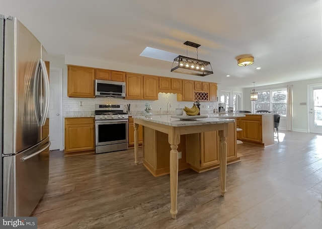 kitchen featuring decorative light fixtures, backsplash, appliances with stainless steel finishes, and wood finished floors