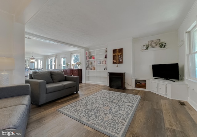 living area featuring a chandelier, visible vents, a fireplace, and wood finished floors