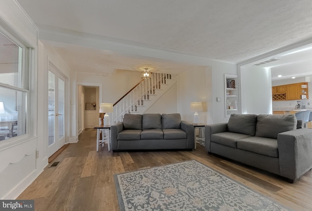 living area featuring stairway, visible vents, and wood finished floors