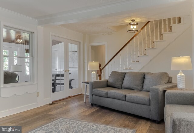 living area featuring wood finished floors, visible vents, stairs, french doors, and crown molding