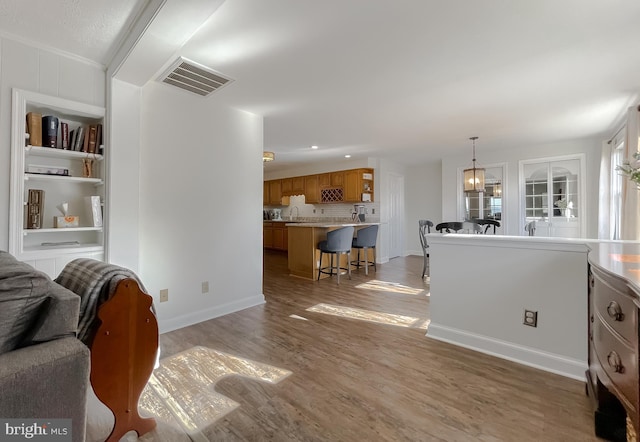 living area with light wood-type flooring, visible vents, and baseboards