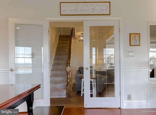 staircase featuring wood finished floors and a wainscoted wall