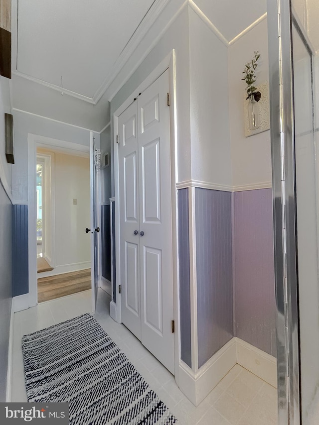 hallway with light tile patterned floors and a wainscoted wall