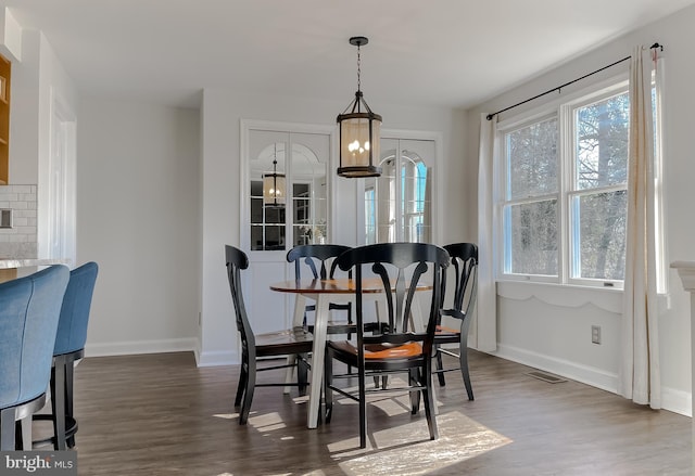 dining area featuring a chandelier, a healthy amount of sunlight, dark wood-type flooring, and baseboards