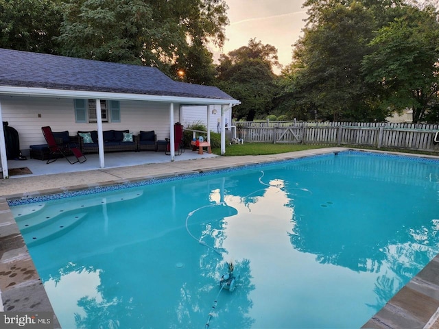 pool at dusk with an outdoor living space, a fenced in pool, fence, and a patio area