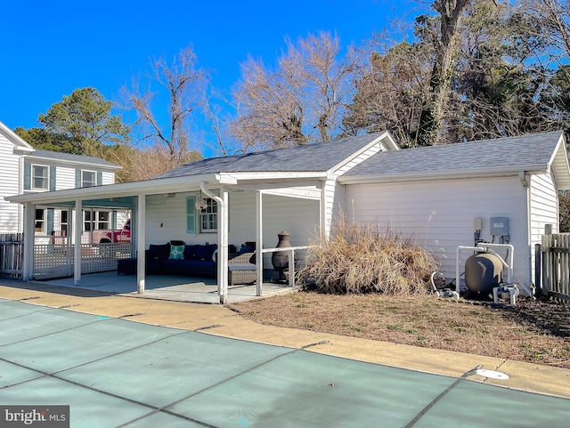 exterior space with an attached carport, driveway, roof with shingles, and fence