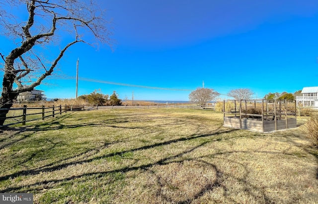 view of yard featuring a rural view, a vegetable garden, and fence