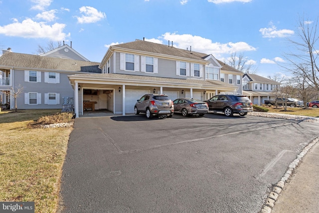 townhome / multi-family property with driveway, a front lawn, and a garage