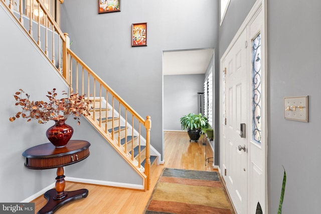 entrance foyer with stairs, wood finished floors, baseboards, and a towering ceiling