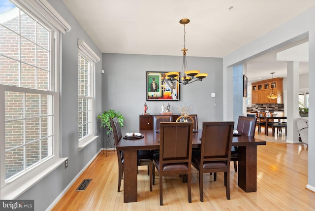 dining room featuring plenty of natural light, light wood-type flooring, visible vents, and a chandelier