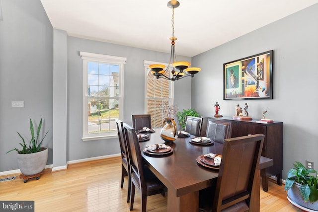 dining room featuring visible vents, wood finished floors, baseboards, and a chandelier