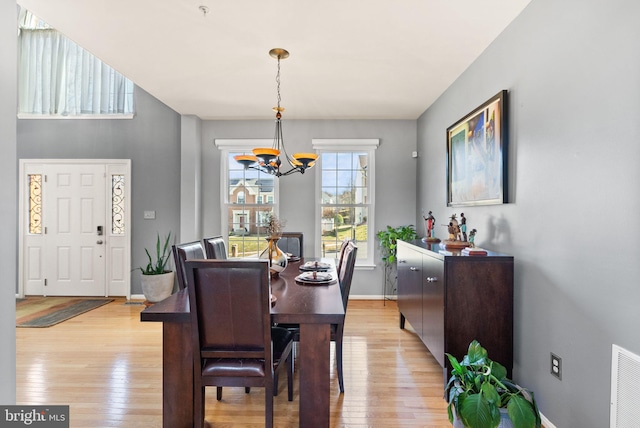 dining area with visible vents, baseboards, light wood-style floors, and an inviting chandelier