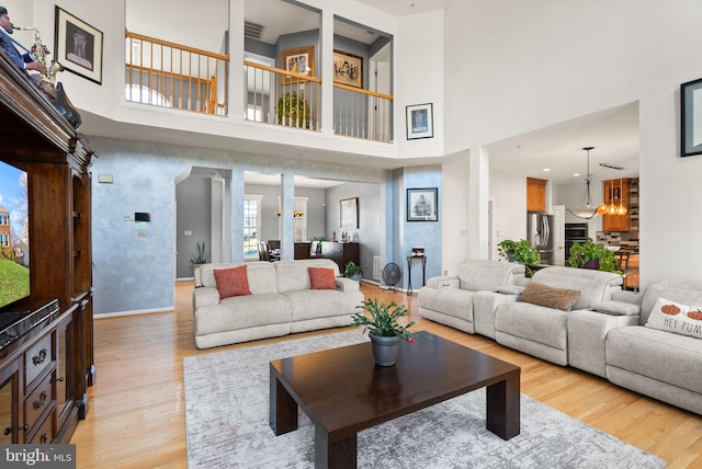 living area featuring a notable chandelier, visible vents, light wood-type flooring, and baseboards