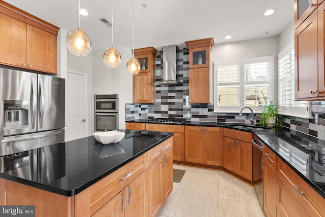 kitchen with visible vents, a sink, backsplash, stainless steel appliances, and wall chimney range hood