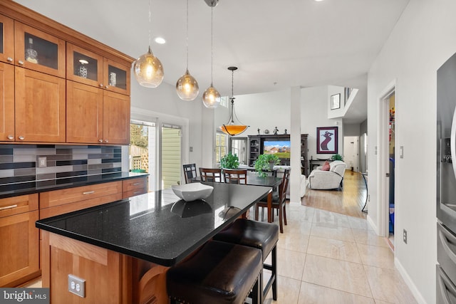 kitchen featuring tasteful backsplash, brown cabinetry, a kitchen island, and a kitchen bar