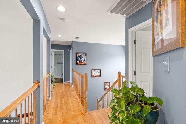 hallway with recessed lighting, visible vents, an upstairs landing, and wood finished floors