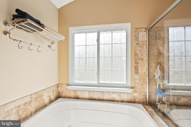 full bath featuring vaulted ceiling, plenty of natural light, and a tub to relax in