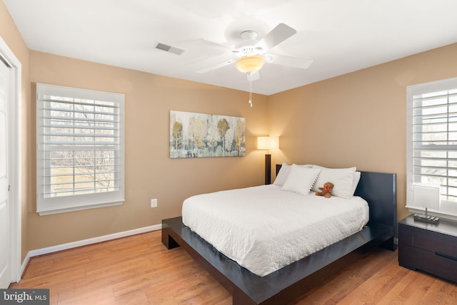 bedroom with visible vents, a ceiling fan, baseboards, and wood finished floors