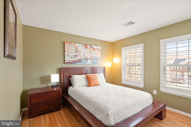 bedroom with visible vents, baseboards, and wood finished floors