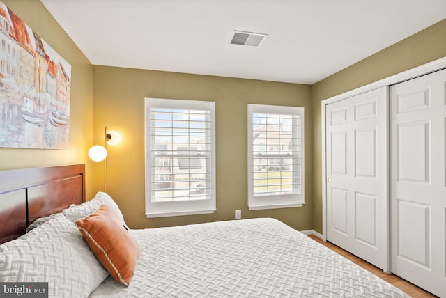 bedroom featuring a closet, visible vents, and wood finished floors