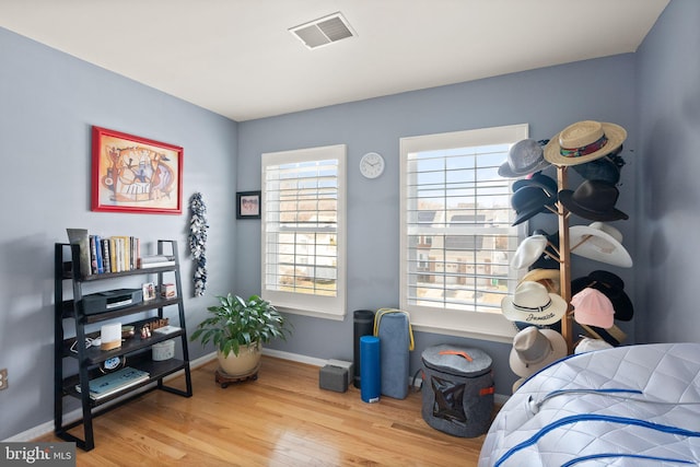 bedroom with visible vents, baseboards, and wood finished floors