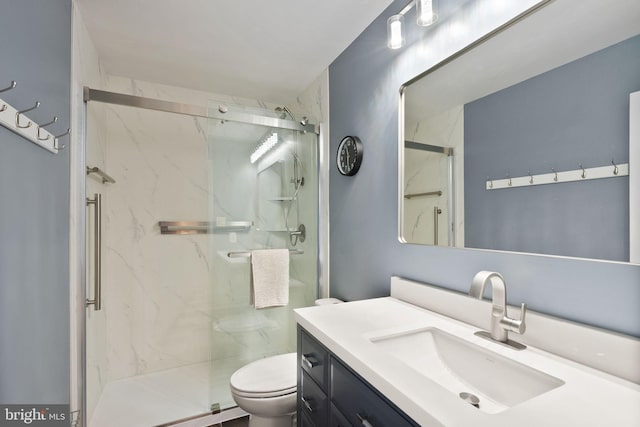 bathroom featuring a marble finish shower, toilet, and vanity