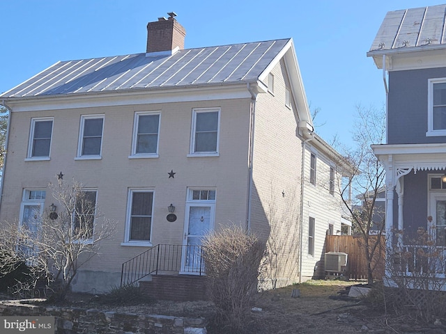 view of front of house featuring brick siding, a chimney, a standing seam roof, and metal roof