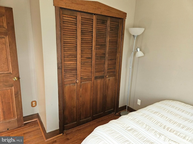 bedroom featuring baseboards, a closet, and dark wood-style flooring