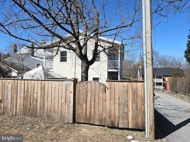 view of property exterior featuring a balcony, a gate, and fence