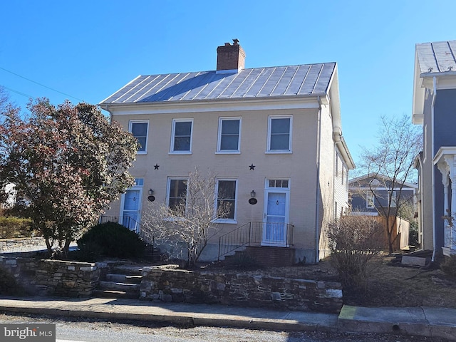 view of front of home with a chimney, a standing seam roof, and metal roof