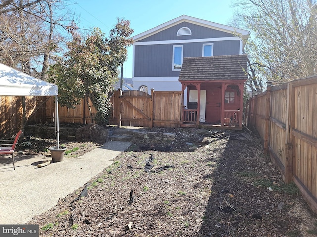 back of house with roof with shingles, a fenced backyard, and a gate