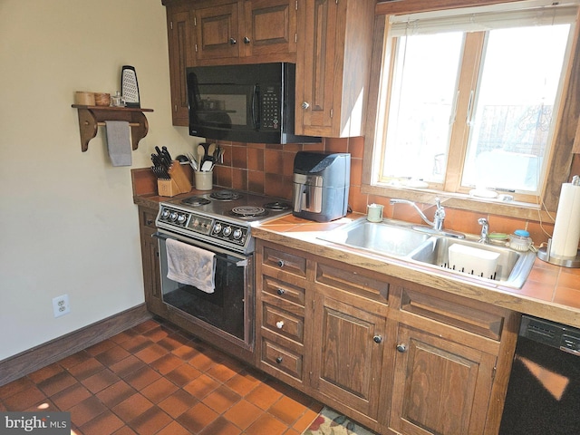 kitchen with black appliances, a sink, light countertops, decorative backsplash, and baseboards