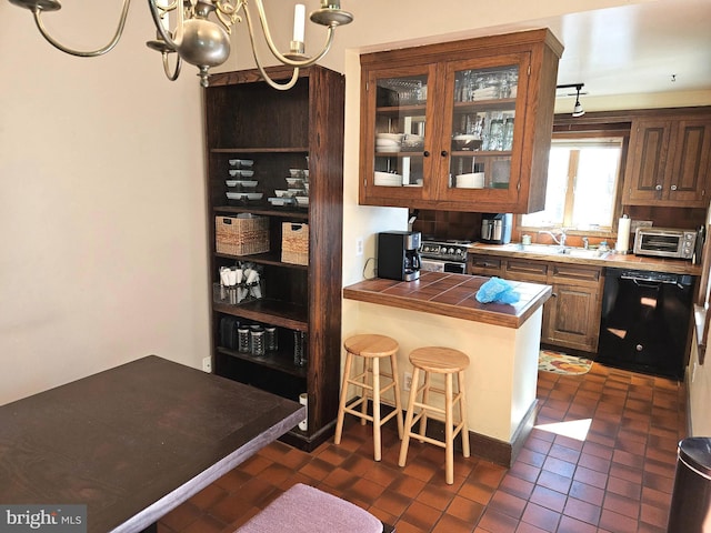 kitchen featuring glass insert cabinets, a toaster, tile countertops, dishwasher, and a kitchen breakfast bar