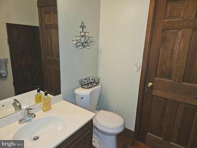 half bath with toilet, vanity, and tile patterned flooring