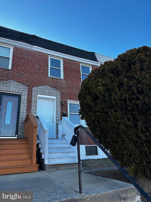 townhome / multi-family property featuring brick siding, stone siding, and a shingled roof