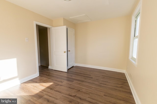 empty room featuring attic access, baseboards, and dark wood-style flooring