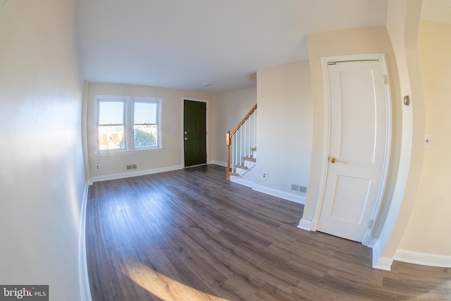 unfurnished room featuring dark wood finished floors, visible vents, stairs, and baseboards