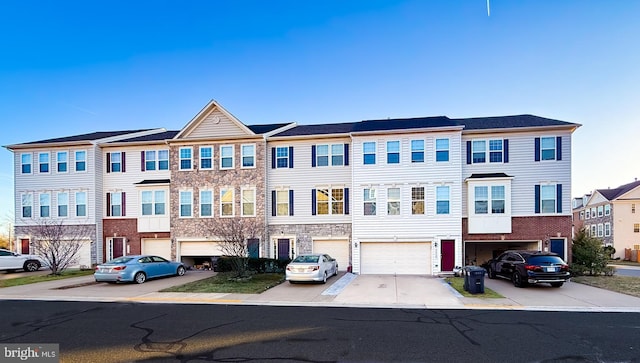 townhome / multi-family property with stone siding, a residential view, driveway, and an attached garage