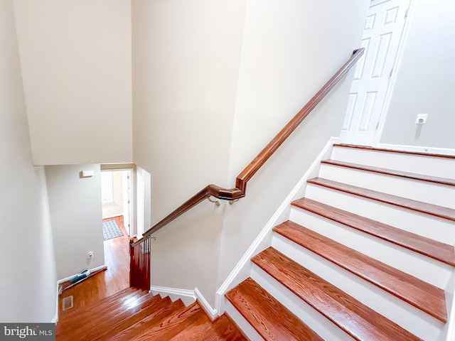 staircase with wood finished floors, visible vents, and baseboards