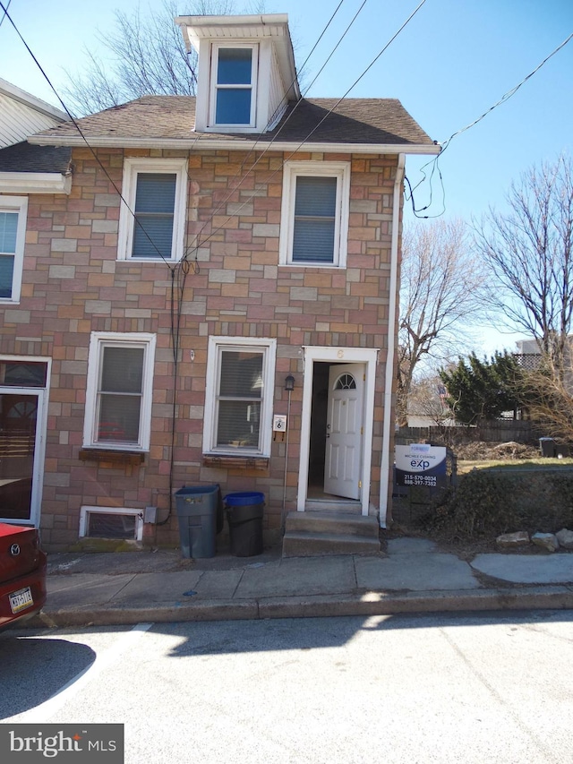 view of front of home featuring stone siding and a shingled roof