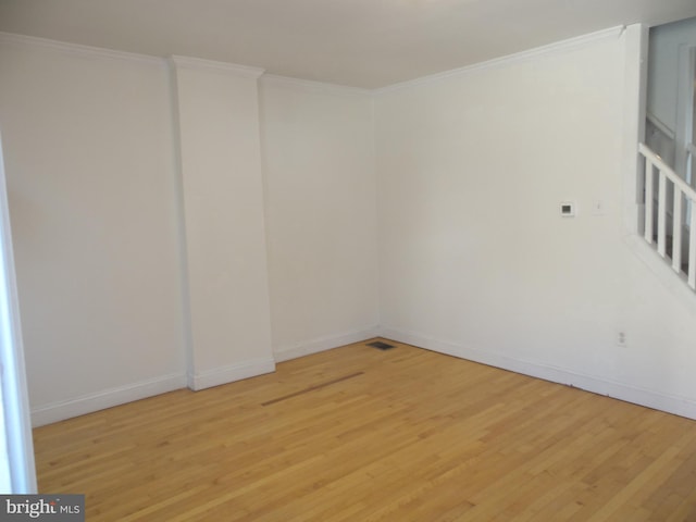 spare room featuring baseboards, light wood-style floors, and ornamental molding