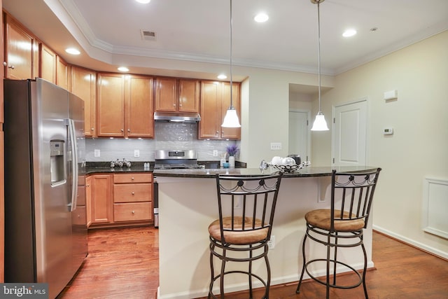 kitchen featuring under cabinet range hood, visible vents, appliances with stainless steel finishes, and wood finished floors