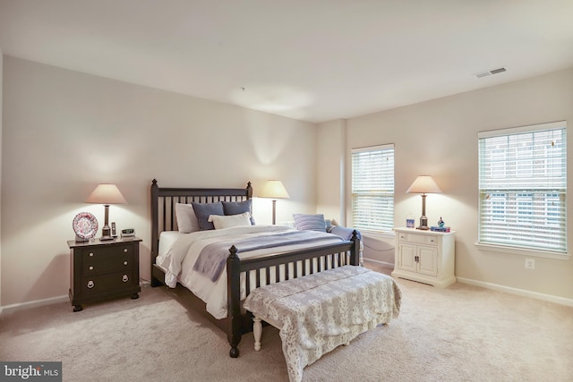 bedroom featuring visible vents, light carpet, and baseboards