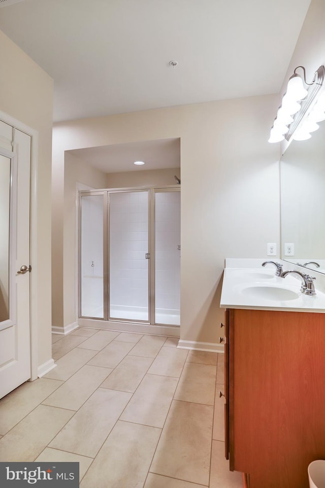 full bathroom featuring tile patterned flooring, a stall shower, vanity, and baseboards