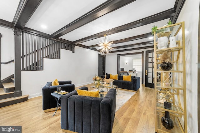 living area featuring stairs, beam ceiling, wood finished floors, and baseboards