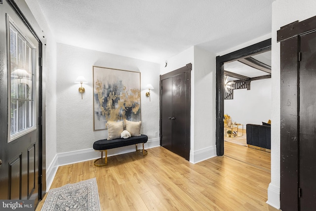 foyer with a textured ceiling, baseboards, and wood finished floors