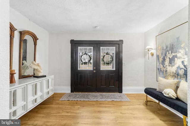 entrance foyer with baseboards, a textured ceiling, and light wood-style flooring